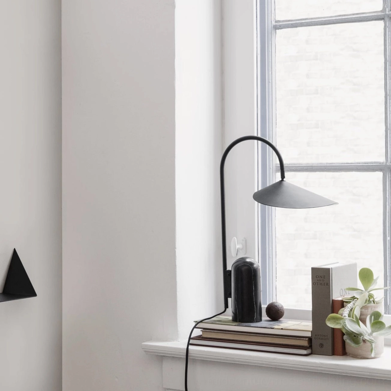 Sculptural black Mono lamp positioned on windowsill with potted succulent and minimalist home decor