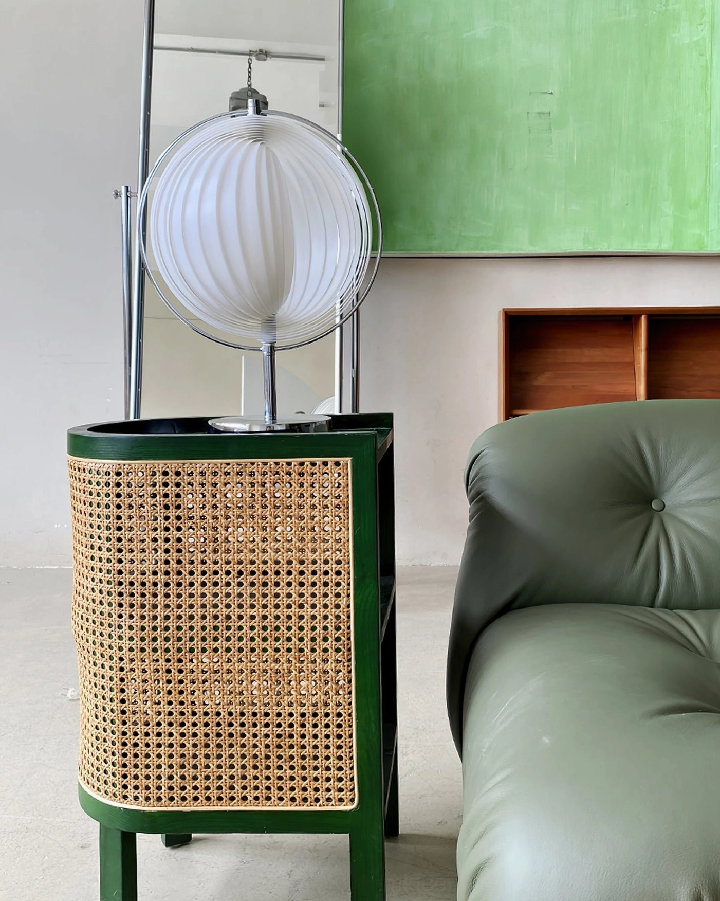 Moon Kare globe table lamp unlit white shade positioned on green rattan side table in contemporary living room