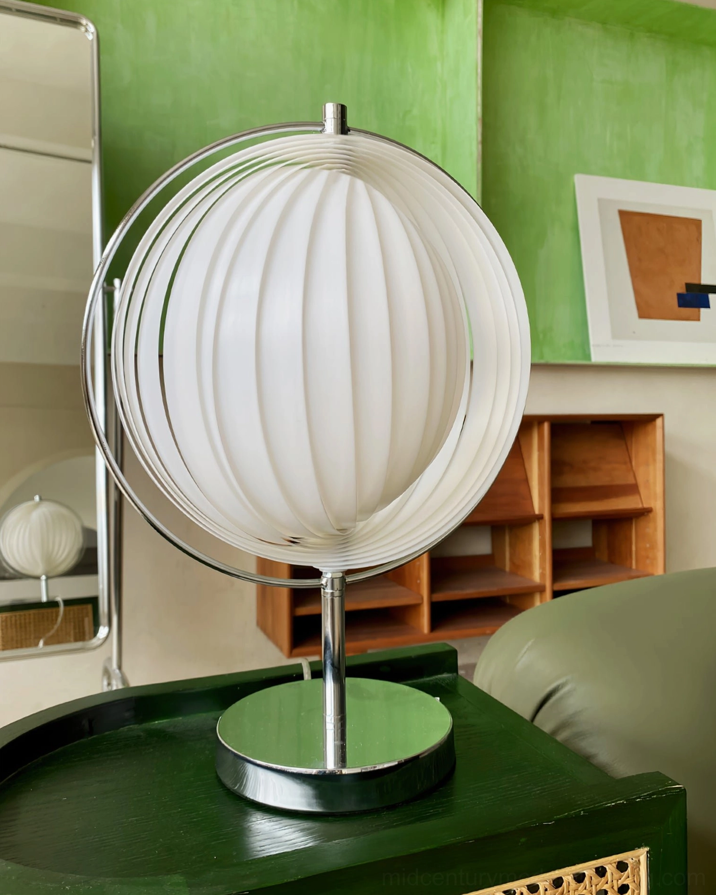 Moon Kare globe table lamp three-quarter side angle showing chrome stand on dark green side table
