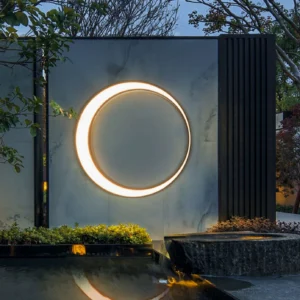 Contemporary outdoor wall lamp illuminated on modern waterscape courtyard exterior showing warm LED glow and minimalist ring silhouette