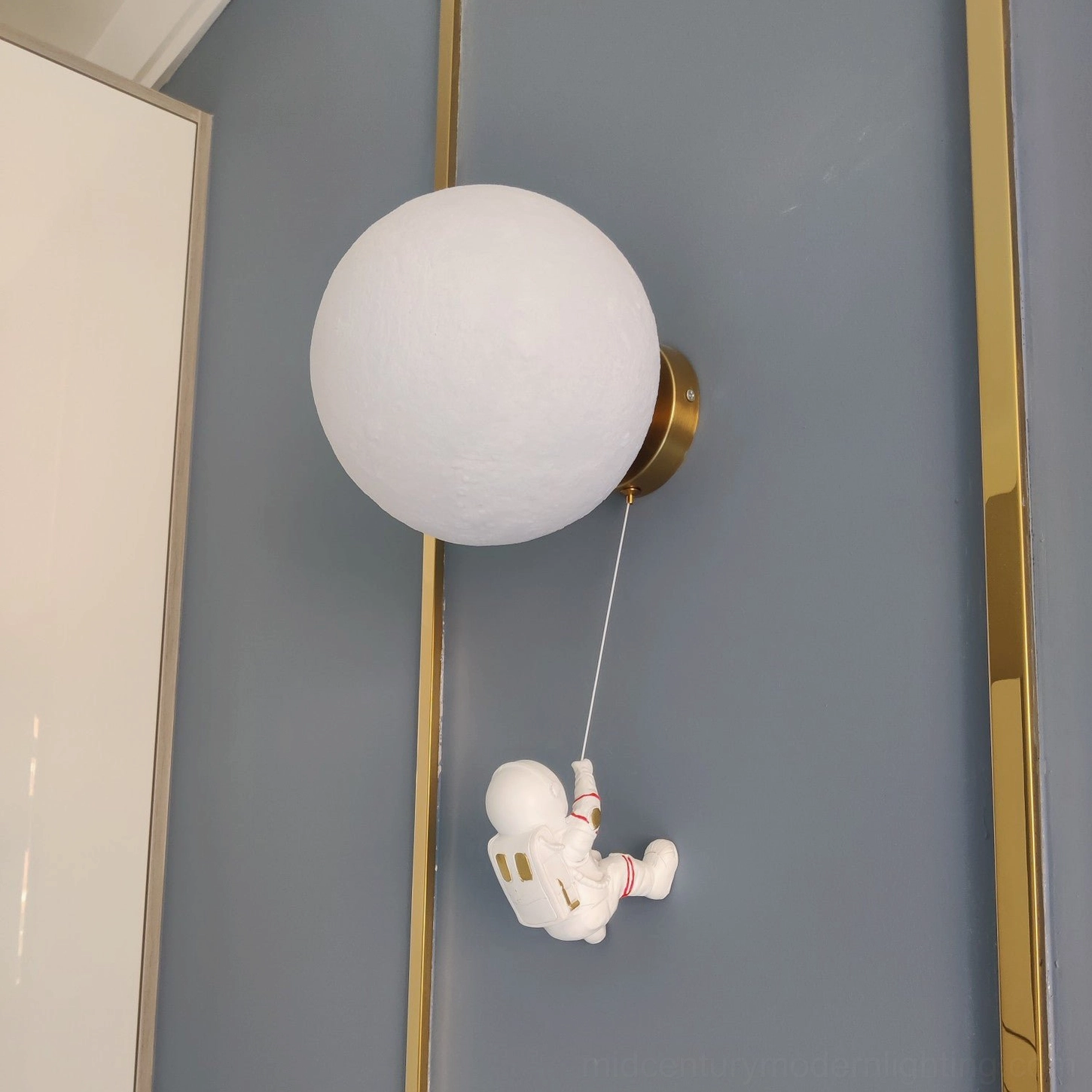 Matte white lunar wall sconce with gold metal mount and wall trim on grey wall