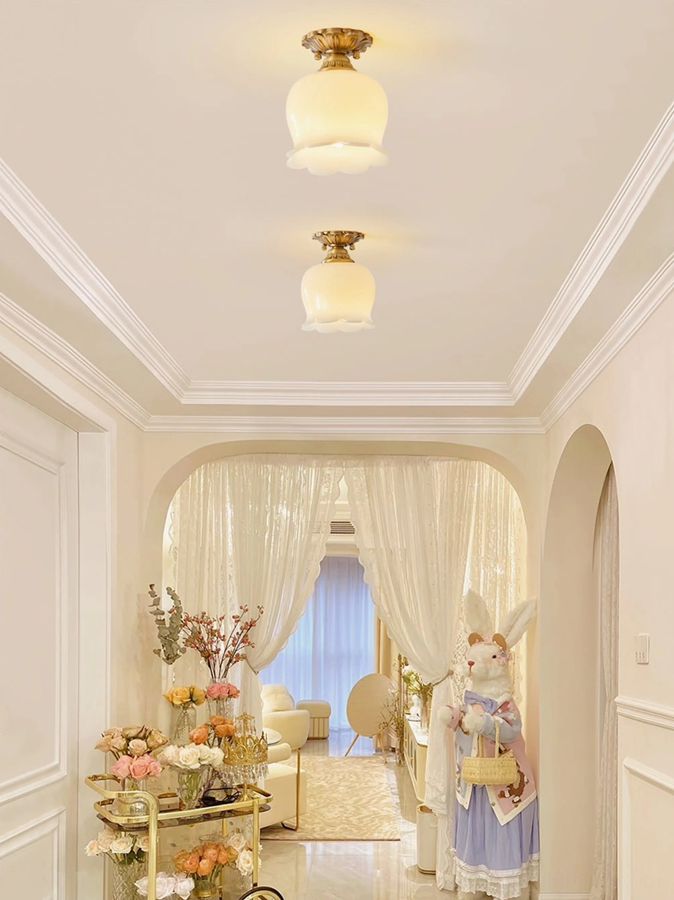 Two matching Morup tulip ceiling lamps in French-style hallway corridor, paired brass and beige fixtures for elegant lighting
