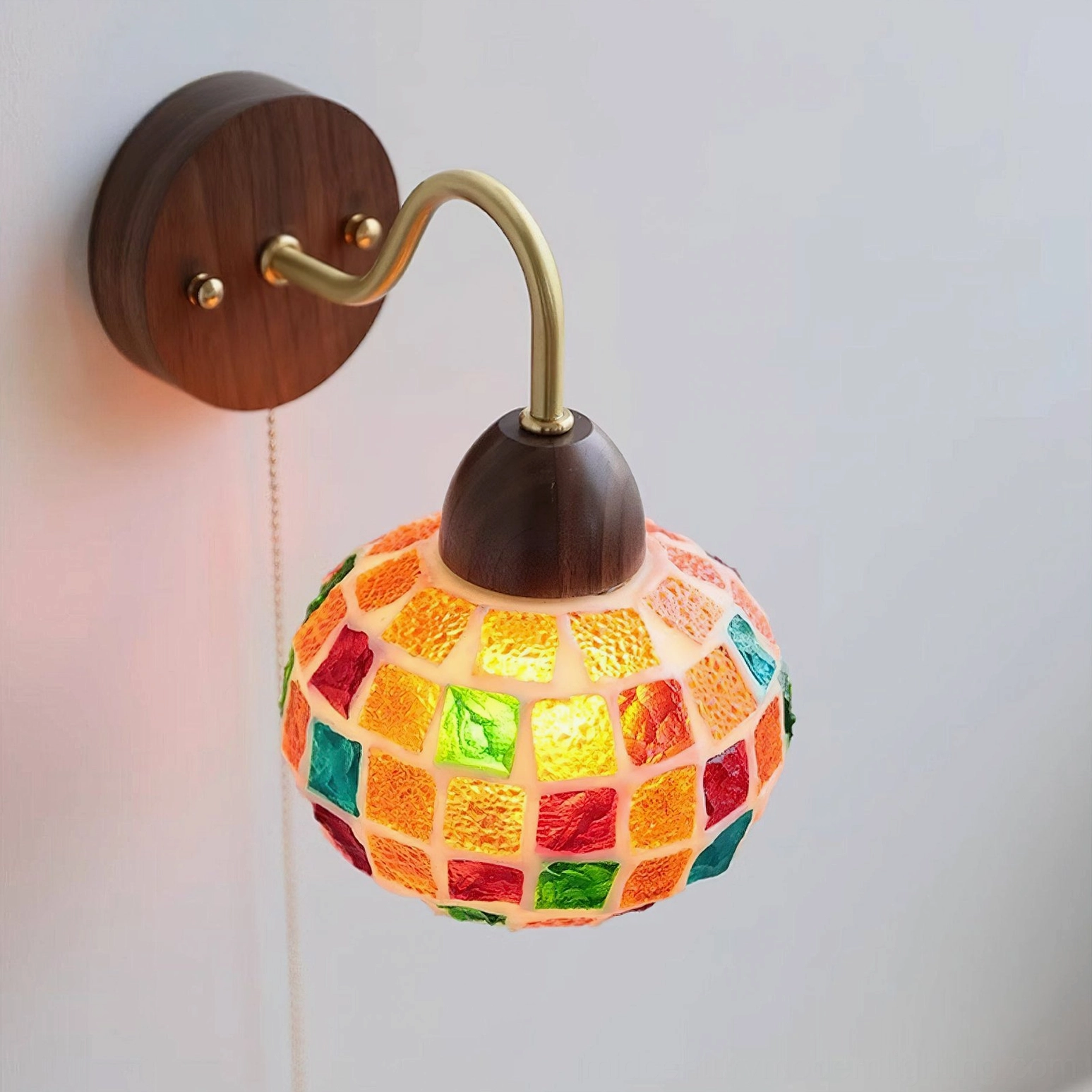 Close-up detail of spherical mosaic glass shade with colorful grid tiles and brass pull chain - side view