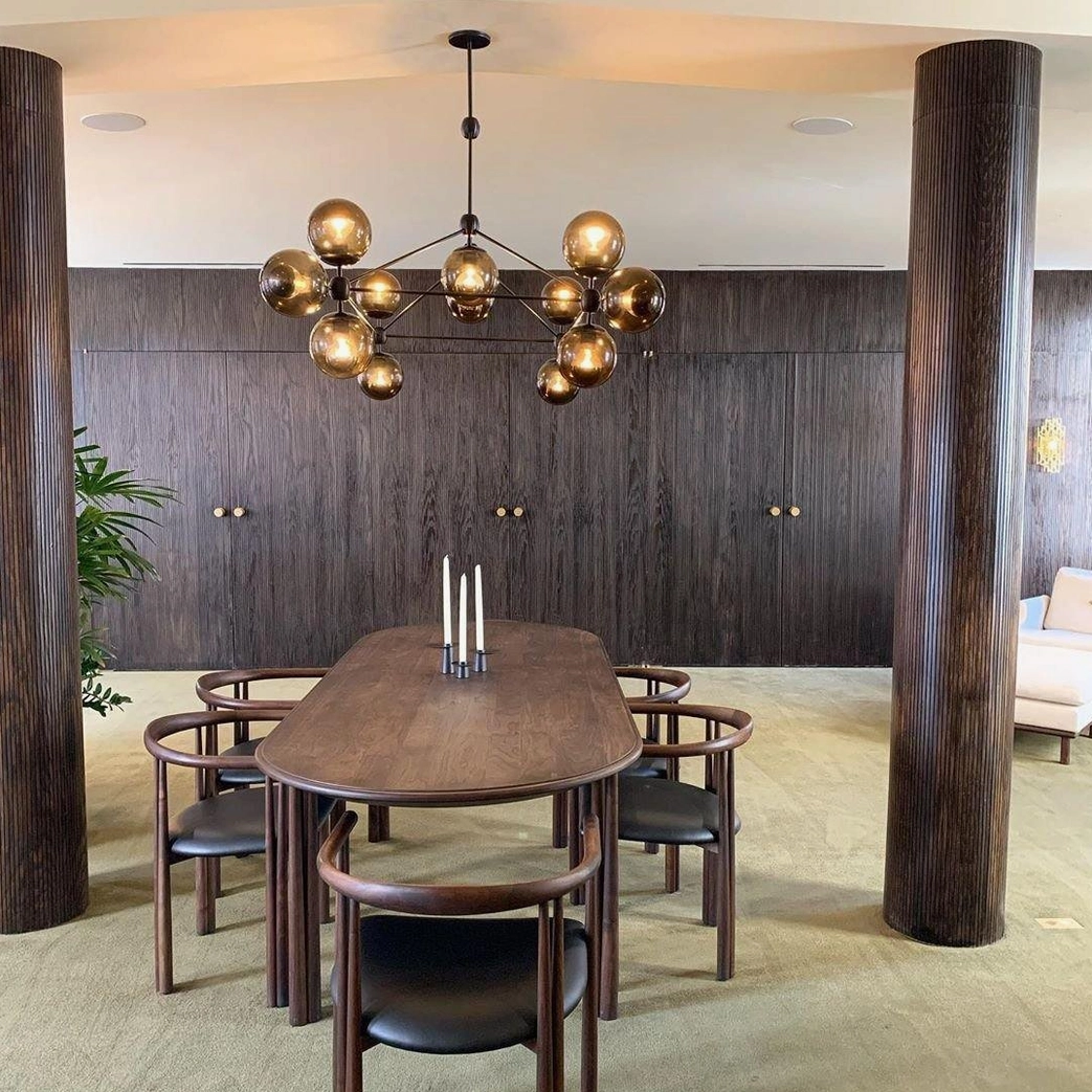 Moto sputnik chandelier in luxury dining room with dark wood cabinetry and tall wooden columns