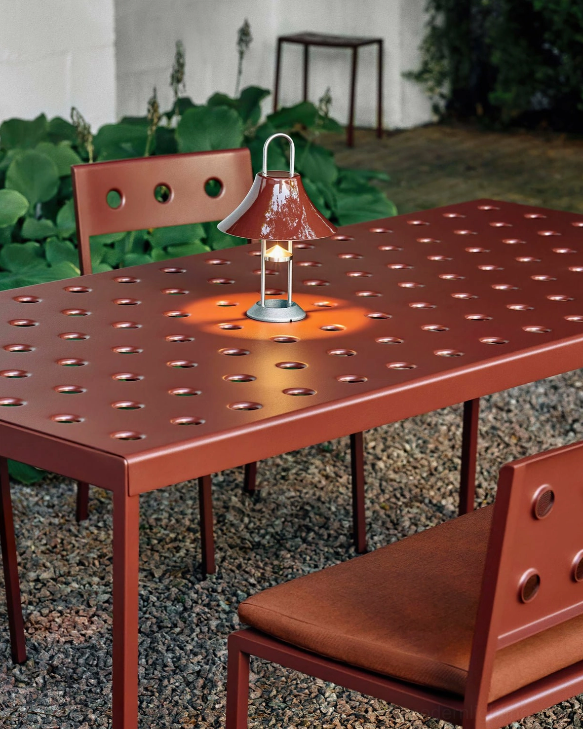 Stainless steel Mousqueton battery-powered table lamp with industrial-modern aesthetic on outdoor display