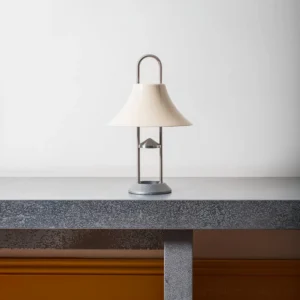 Cordless modern portable lamp with off-white acrylic shade and brushed metal frame displayed on concrete table indoors