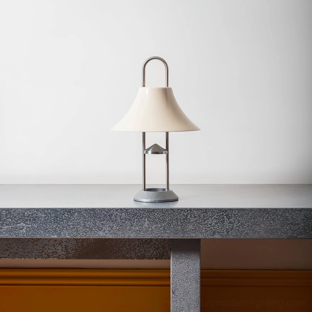 Cordless modern portable lamp with off-white acrylic shade and brushed metal frame displayed on concrete table indoors