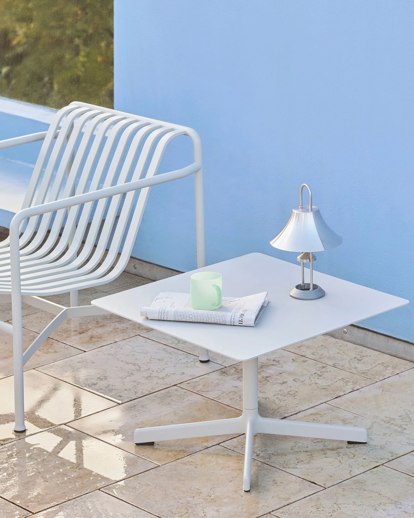 Off-white Mousqueton cordless lamp positioned on white outdoor seating area with modern contemporary furniture