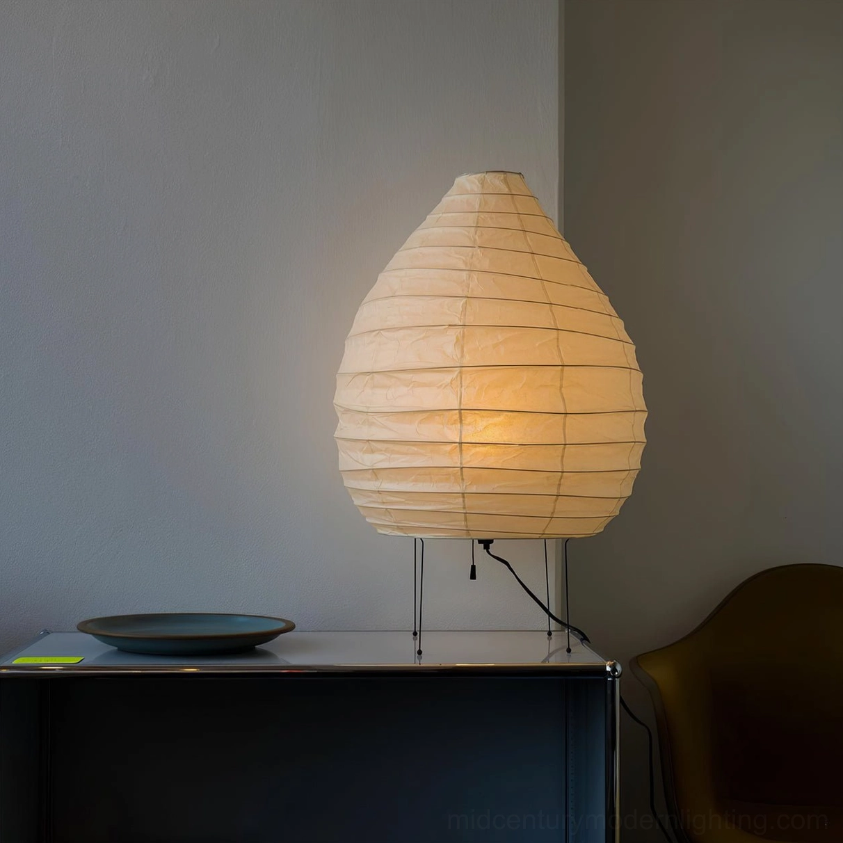 Warm glowing mulberry paper table lamp beside decorative plate, ambient lighting mood