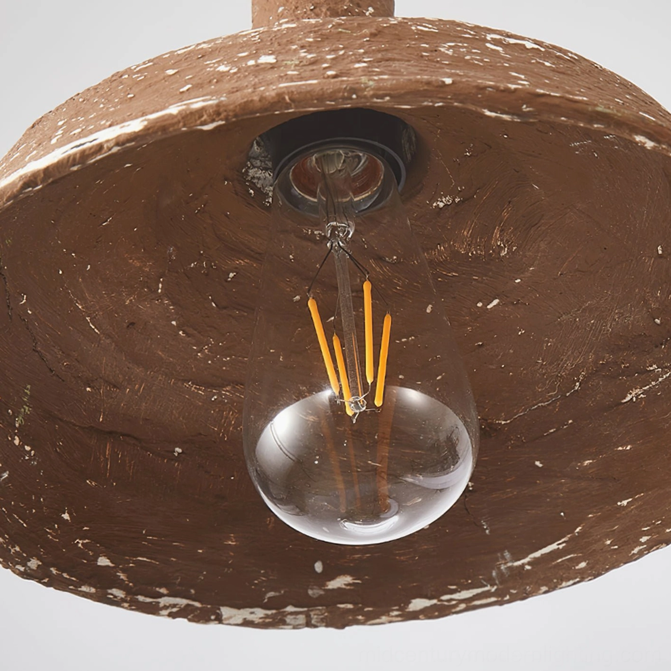 Close-up detail of Mulino pendant interior showing exposed Edison bulb and rough distressed metal surface texture