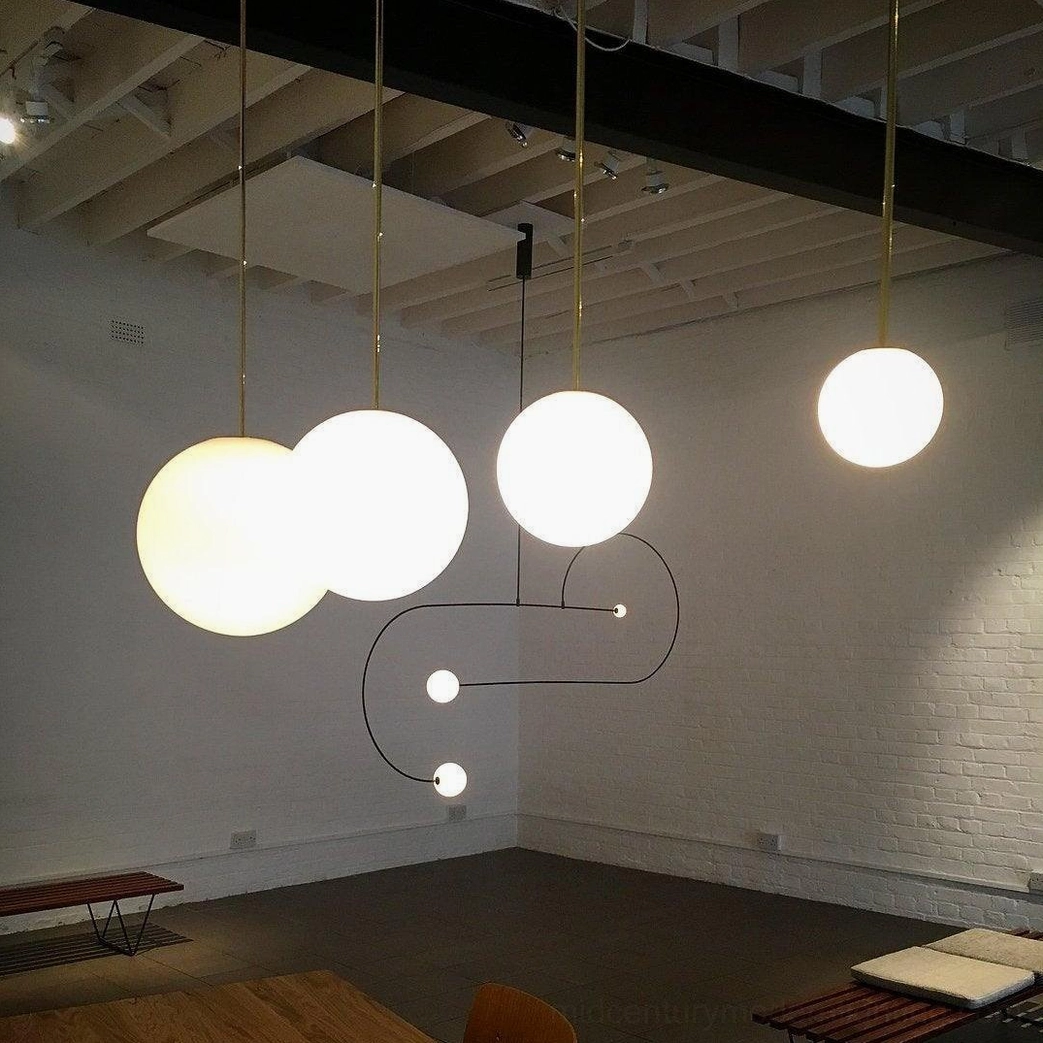 Multiple brass globe pendant lights installed in industrial loft space with modern aesthetic