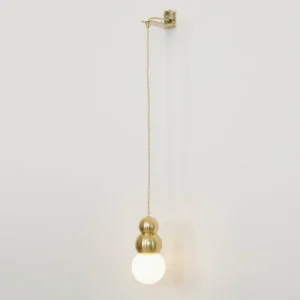 Multiple stacked brass ball pendant lights mounted on white wall, mid-century modern wall sconce cluster