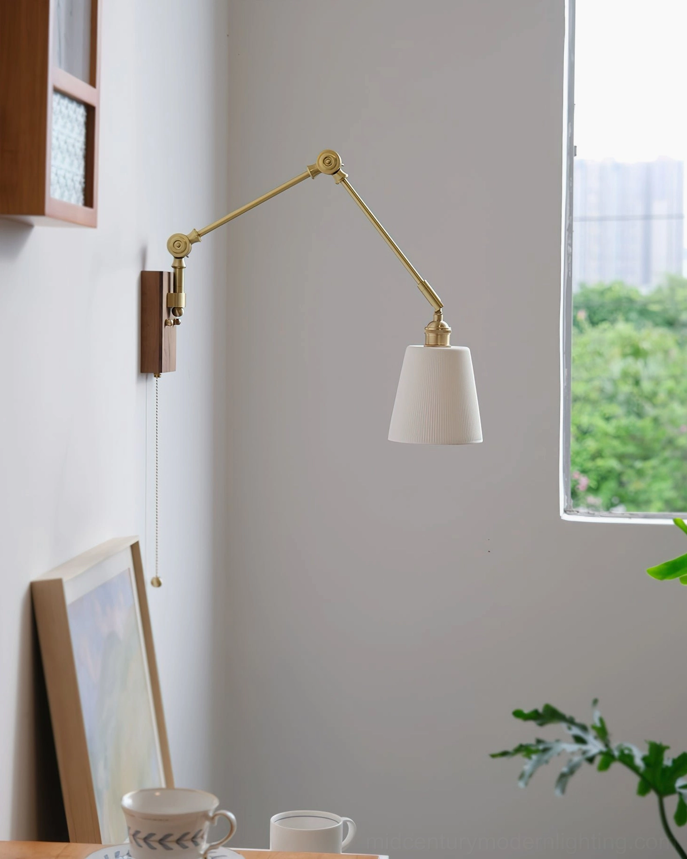 Unlit murale swing arm sconce with textured pleated shade positioned in minimalist dining corner with natural window light