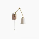 Murale swing arm wall lamp with brass articulated arm and walnut base, featuring ribbed white ceramic shade in minimalist studio setting
