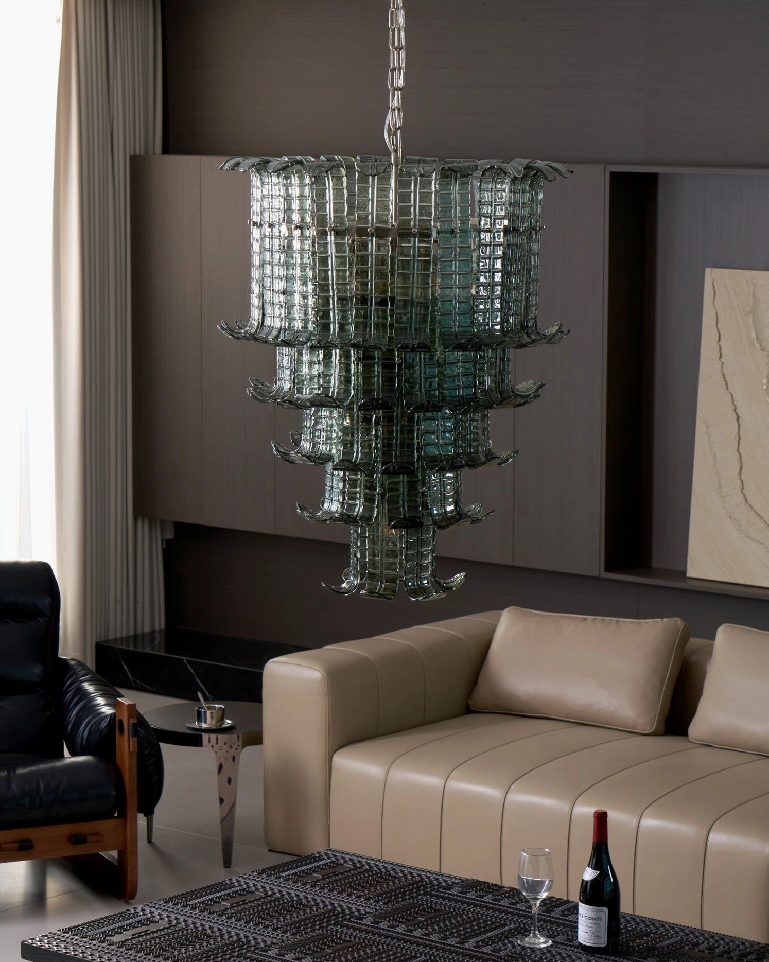 Murano tiered chandelier in modern neutral tone living room with dark wood accent wall, architectural statement lighting piece