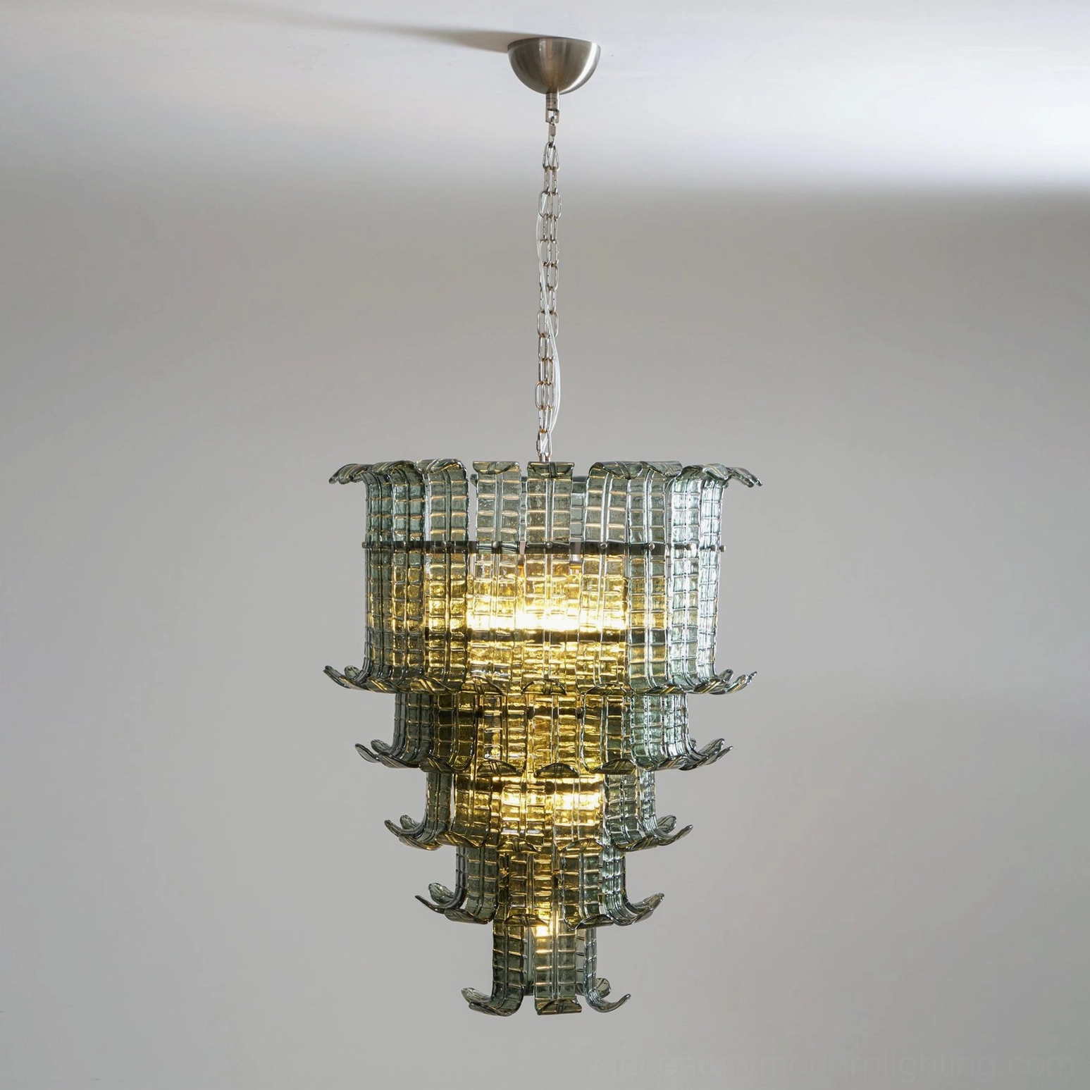 Illuminated murano tiered glass chandelier close-up with warm glowing internal light, polished metal hanger and structural details