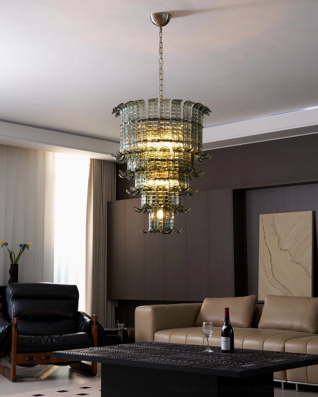 Illuminated murano tiered chandelier emitting warm ambient light in contemporary living room with beige sofa and leather accent chair