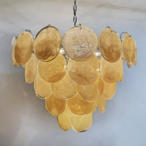 Close-up front view of stacked tiered amber Murano glass discs on polished metal chandelier frame