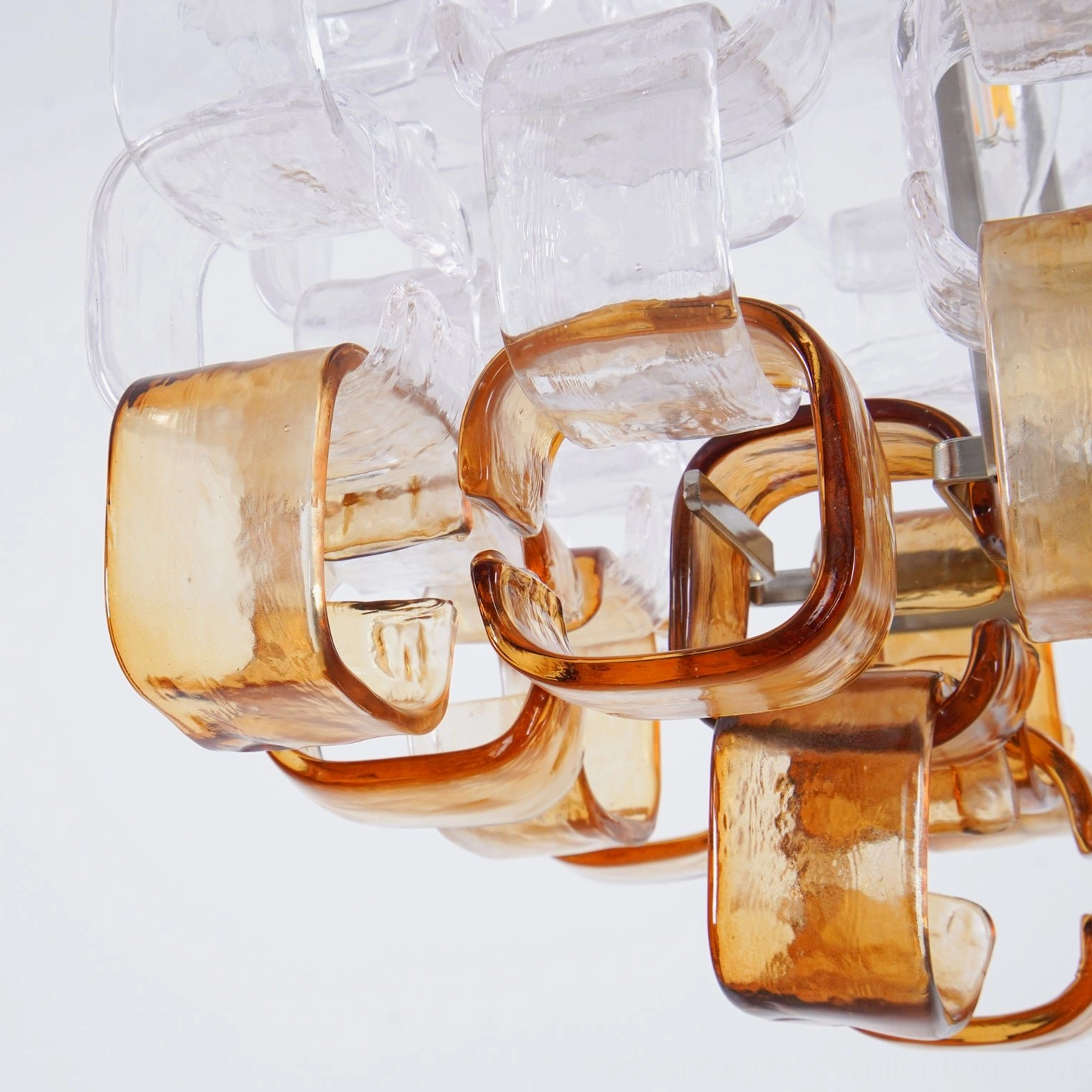 Macro detail view of curved textured amber and clear glass pendant pieces for Elodie Murano chandelier construction