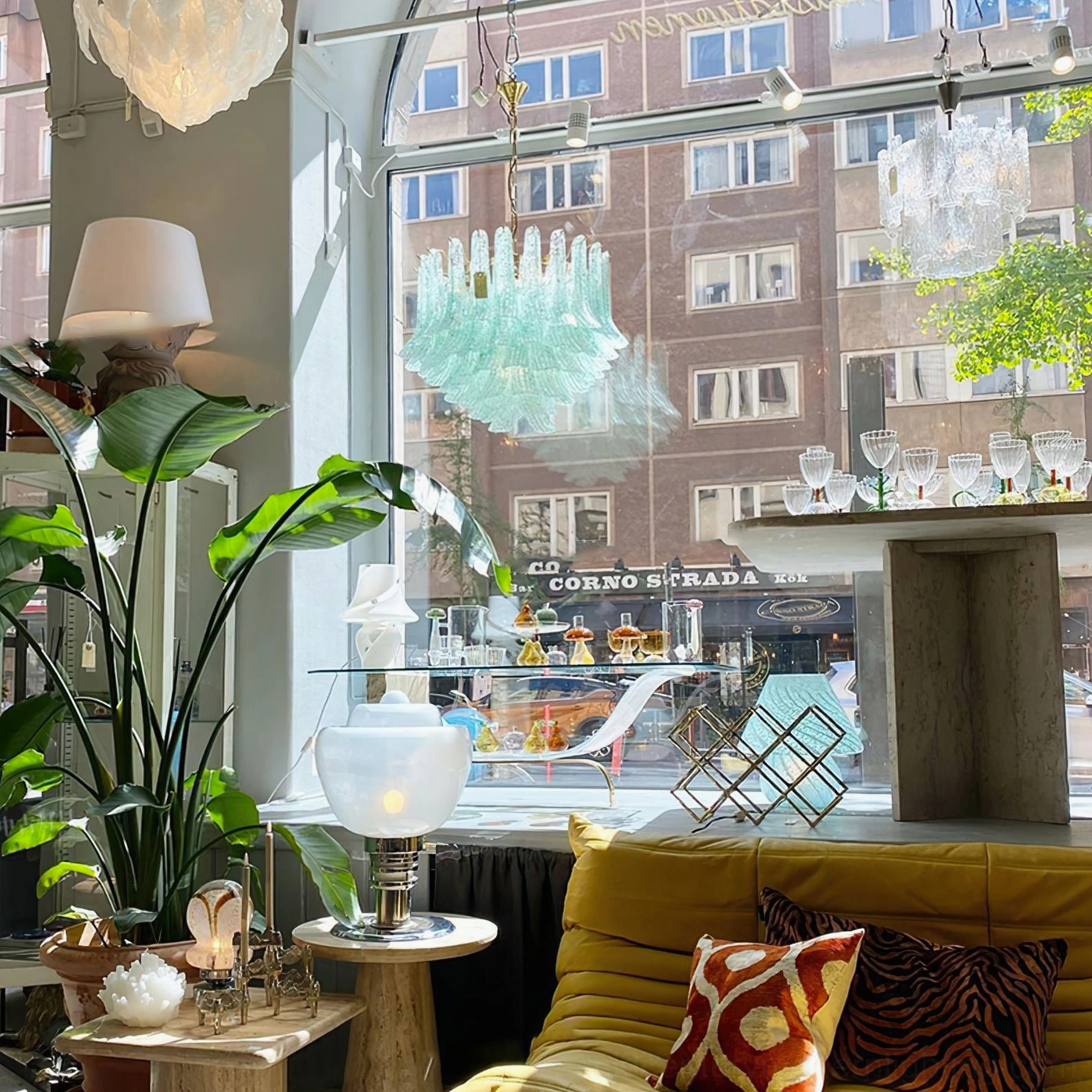 Murano green chandelier installed in home furnishing shop displaying multi-tiered green glass shades paired with indoor sofa and plants