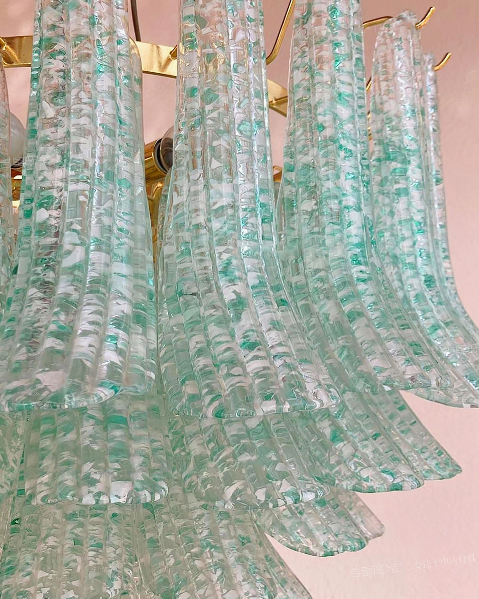 Close-up detail of Murano chandelier glass components showing long ribbed glass panels with green flecks and gold mounting hardware