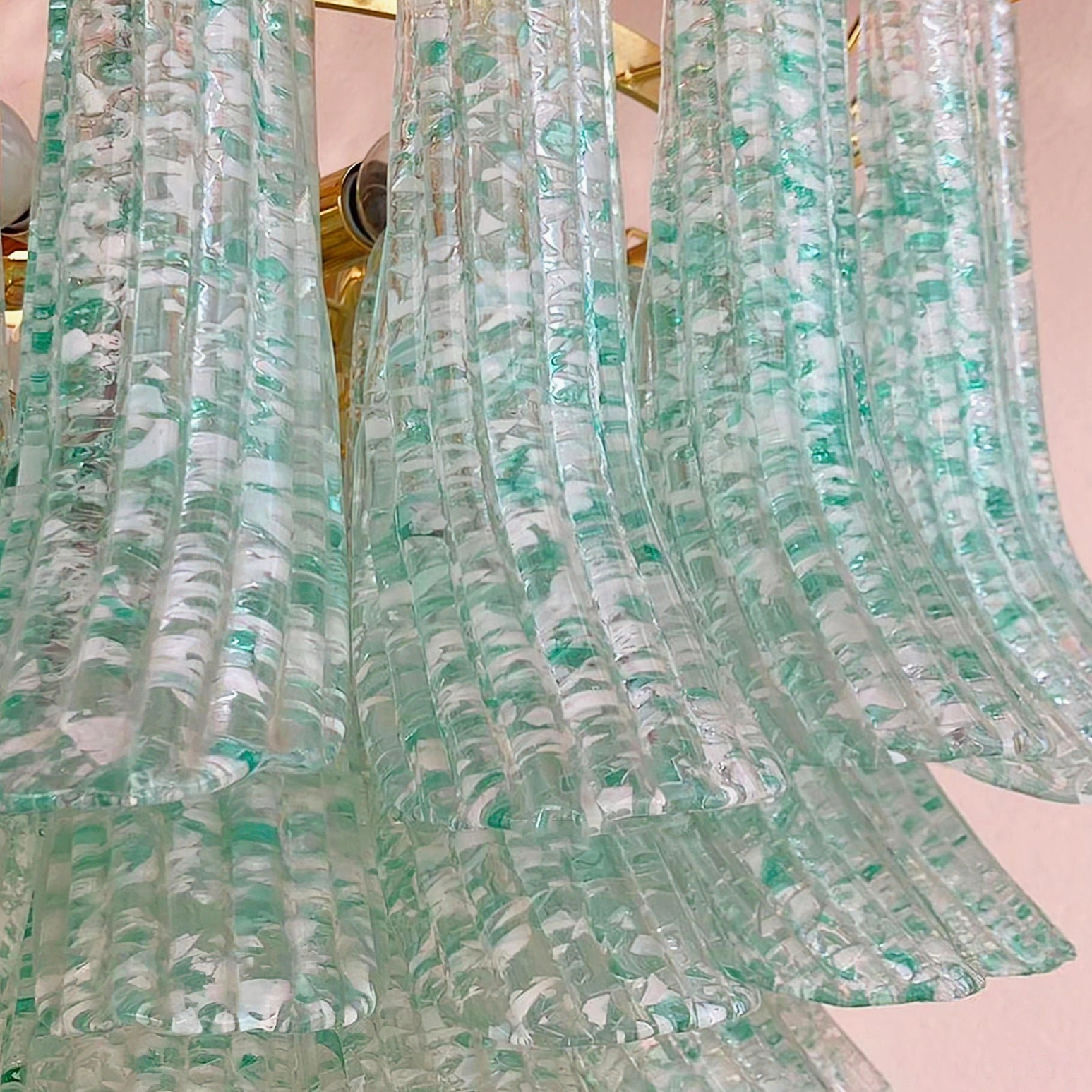 Layered Murano green glass chandelier shades with ruffled design and ribbed textured surface displaying green speckles, close-up front view