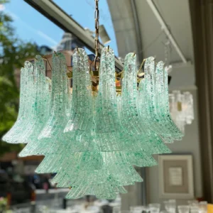 Handcrafted Murano green glass chandelier in vintage boutique setting, low angle view displaying textured ribbed glass with gold speckles and metal frame