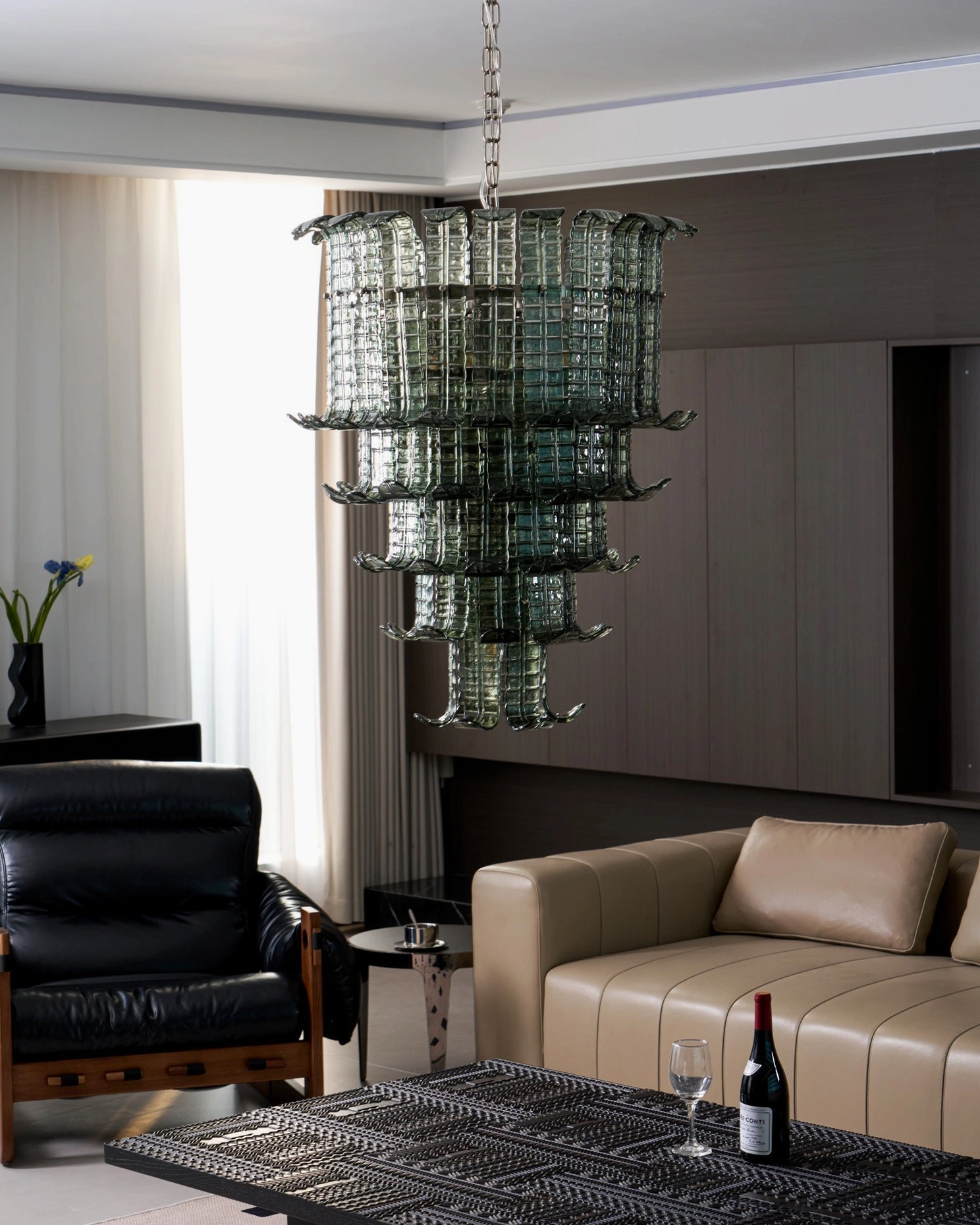 Murano smoked green tiered glass chandelier silhouette in contemporary living room with tan leather accent chair and neutral tones