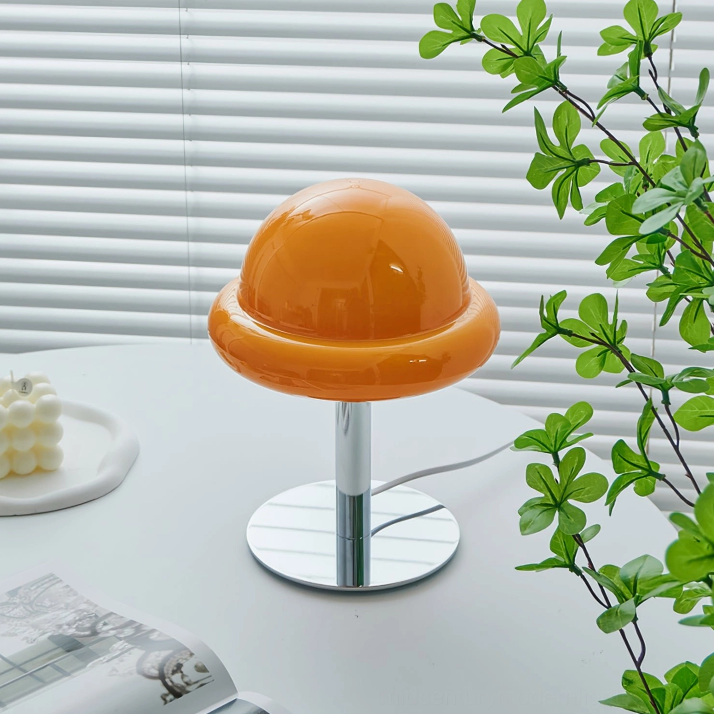 Close-up detail of orange glass mushroom lamp dome with smooth glossy reflective surface and blind backdrop