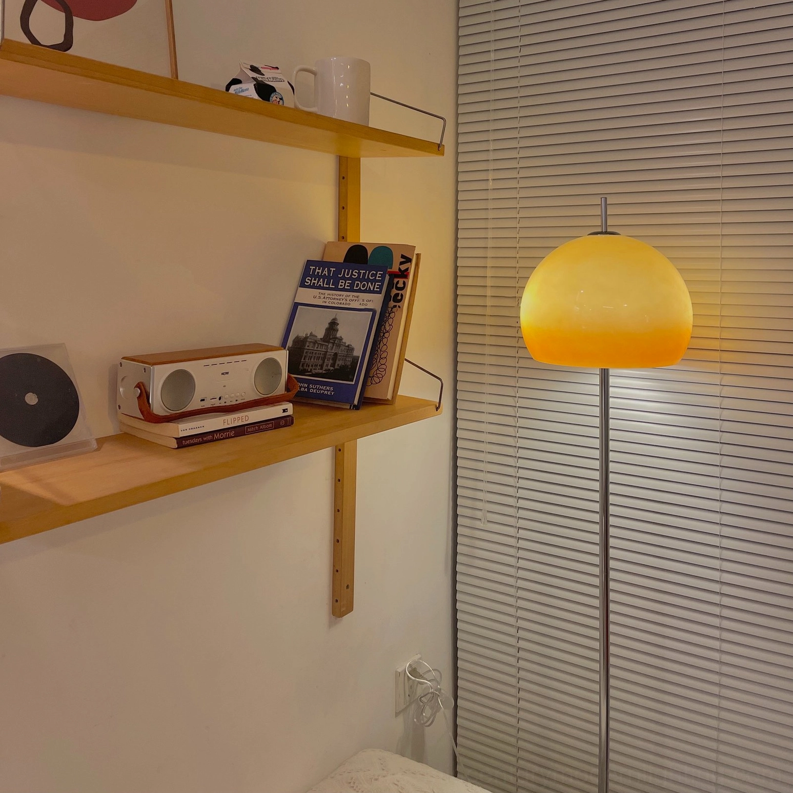 Mushroom floor lamp on wooden shelf with venetian blinds background, front side view