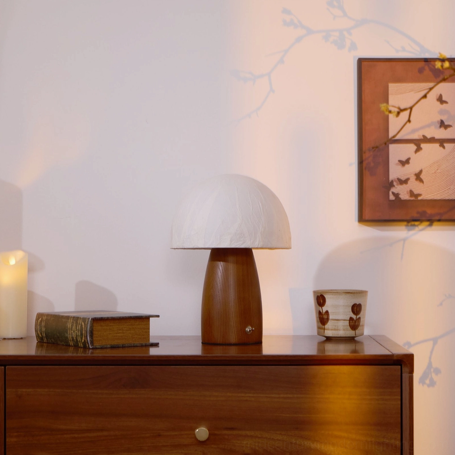 Mushroom lamp three-quarter side shot on wooden dresser with branch wall shadow and candle