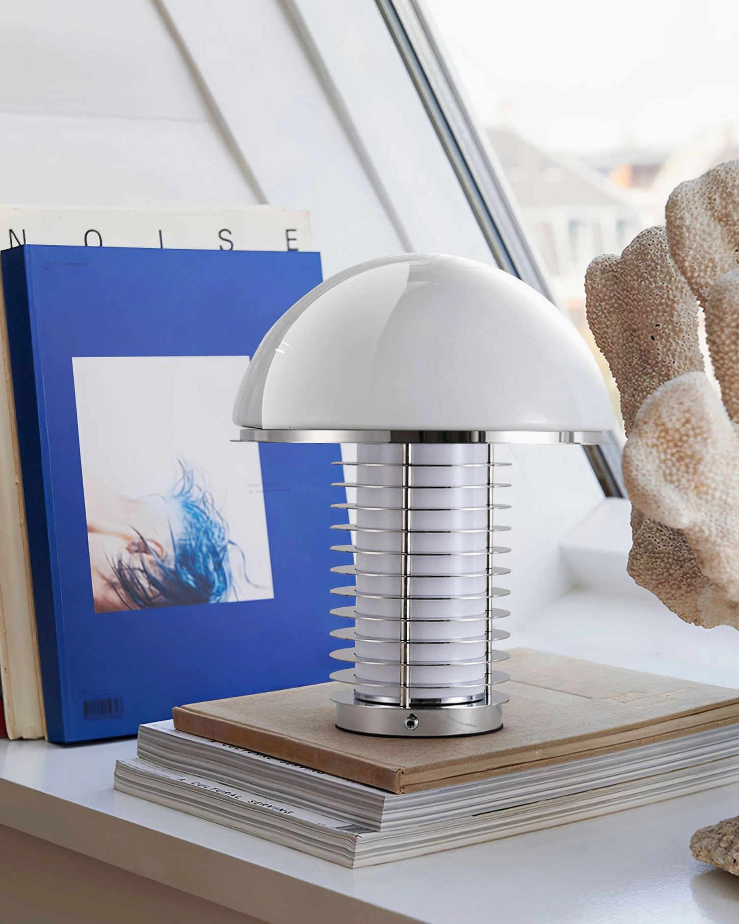 Table lamp positioned on stacked books and art book decor on home desk shelf display