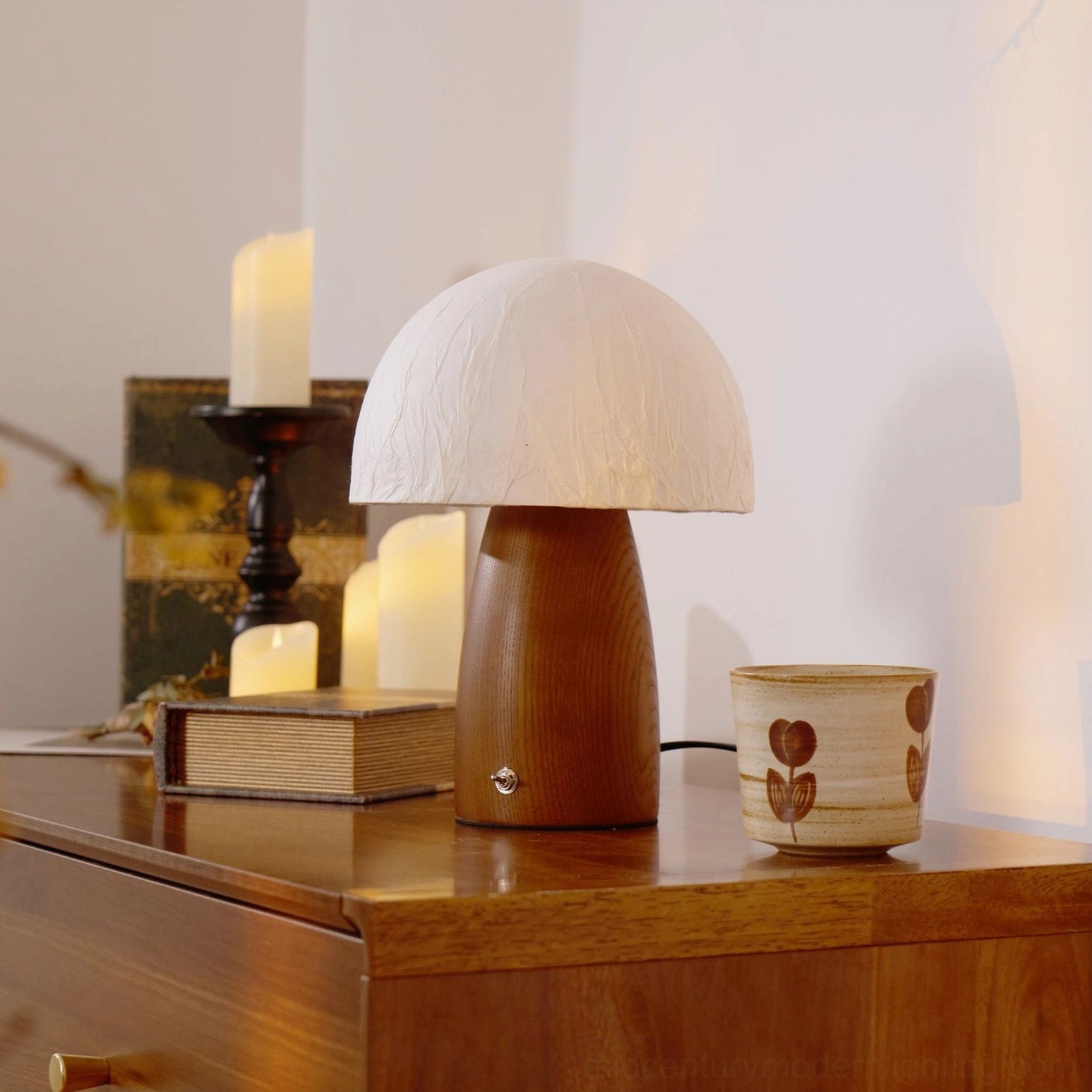 Side three-quarter view of mushroom table lamp on wooden nightstand with candles and vintage decor