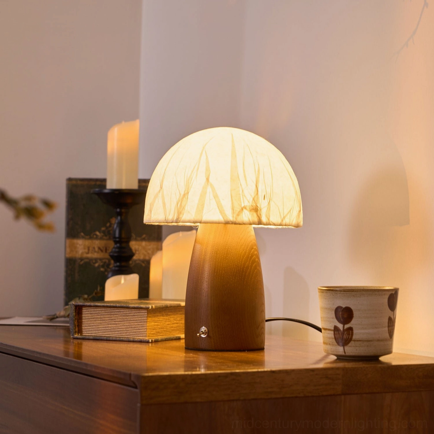 Mushroom table lamp three-quarter view on vintage wooden nightstand with pillar candle and old book