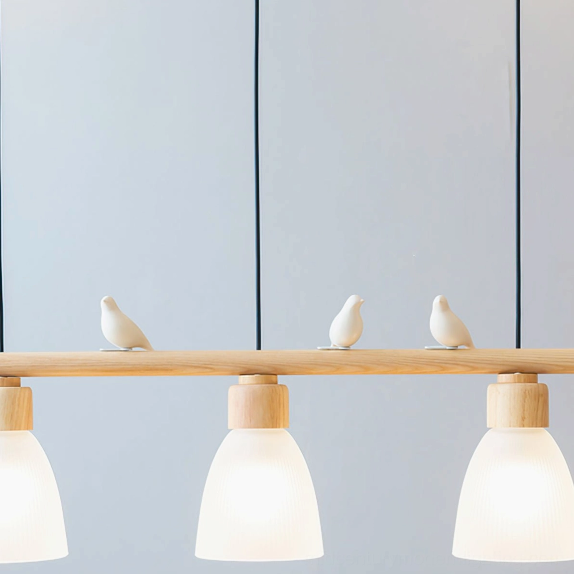 Muto Bird Chandelier close-up view - frosted glass shade detail and bird ornament with plant background