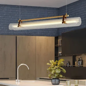 Contemporary linear pendant light fixture in modern kitchen space with brass hardware and leather accent - wide interior perspective