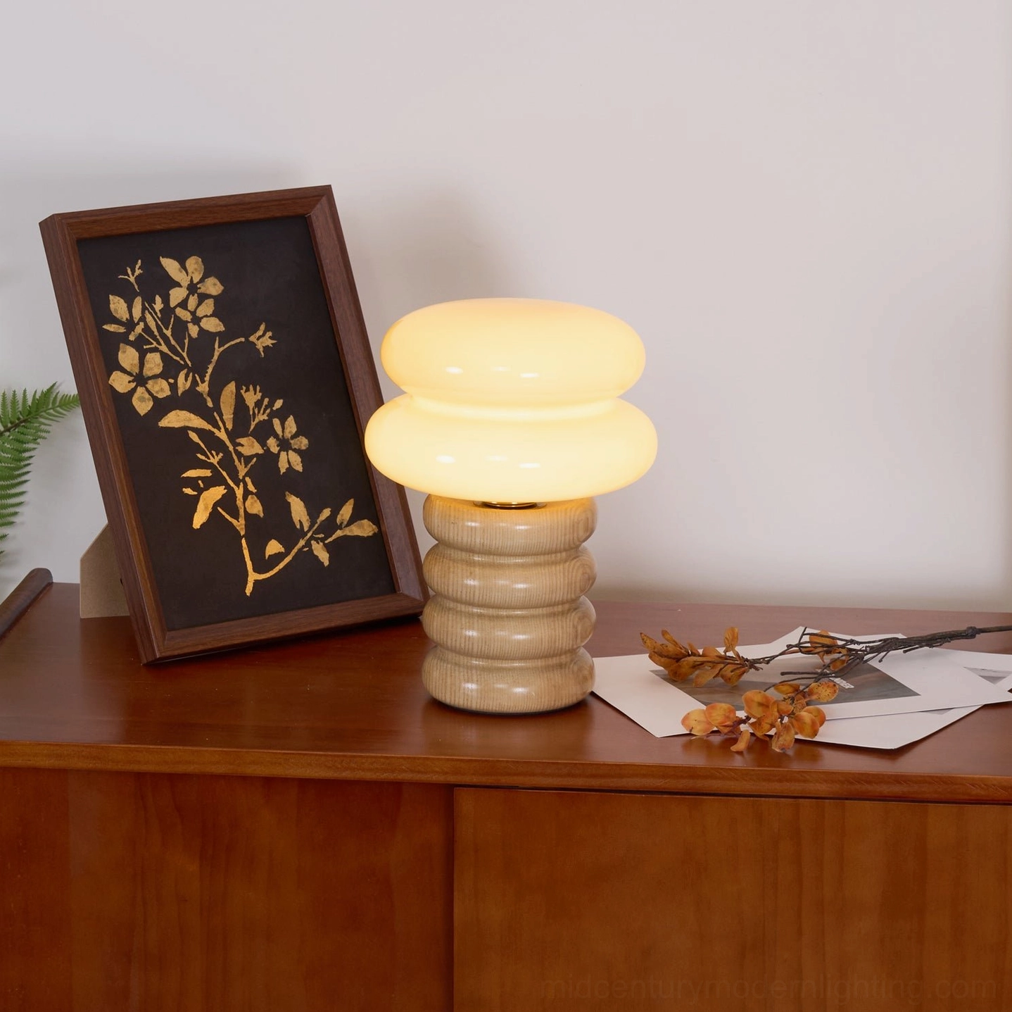 Lit Napako mini table lamp with turned solid ash wood base and frosted glass shade creating warm light on home sideboard