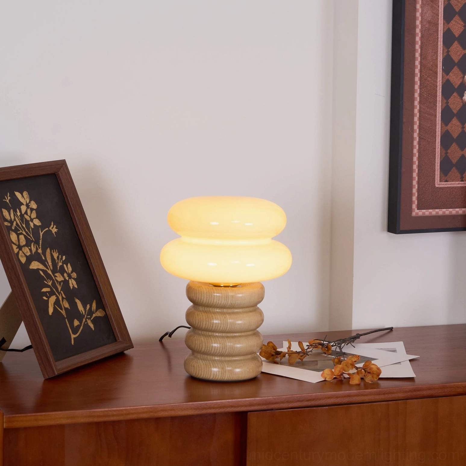 Illuminated Napako table lamp with warm glowing frosted glass shade creating ambient light on home sideboard display