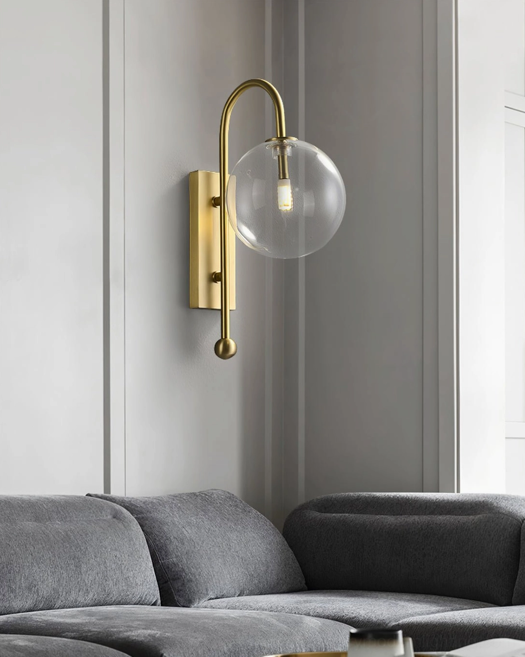 Curved arm metal wall sconce with glass sphere in modern living room neutral decor setting