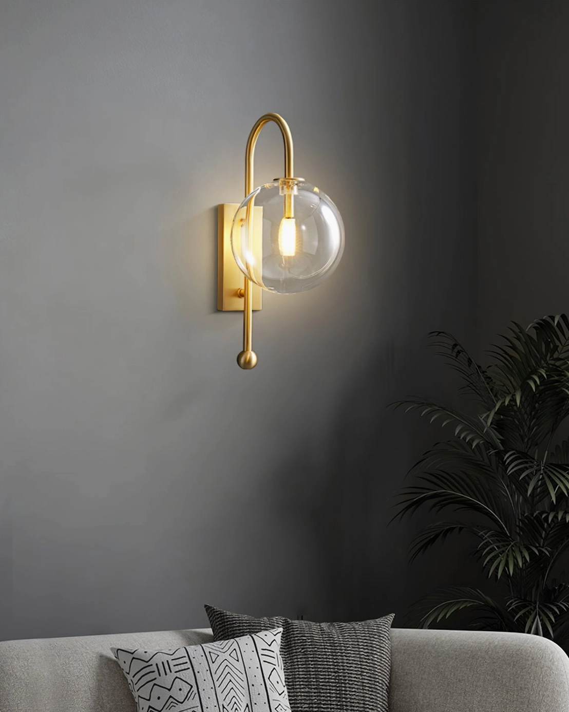 Minimalist copper wall lamp with spherical glass globe above grey sofa in modern living space