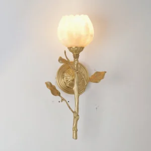 Illuminated Natalia alabaster wall sconce showing soft ethereal glow through carved shade on white interior wall