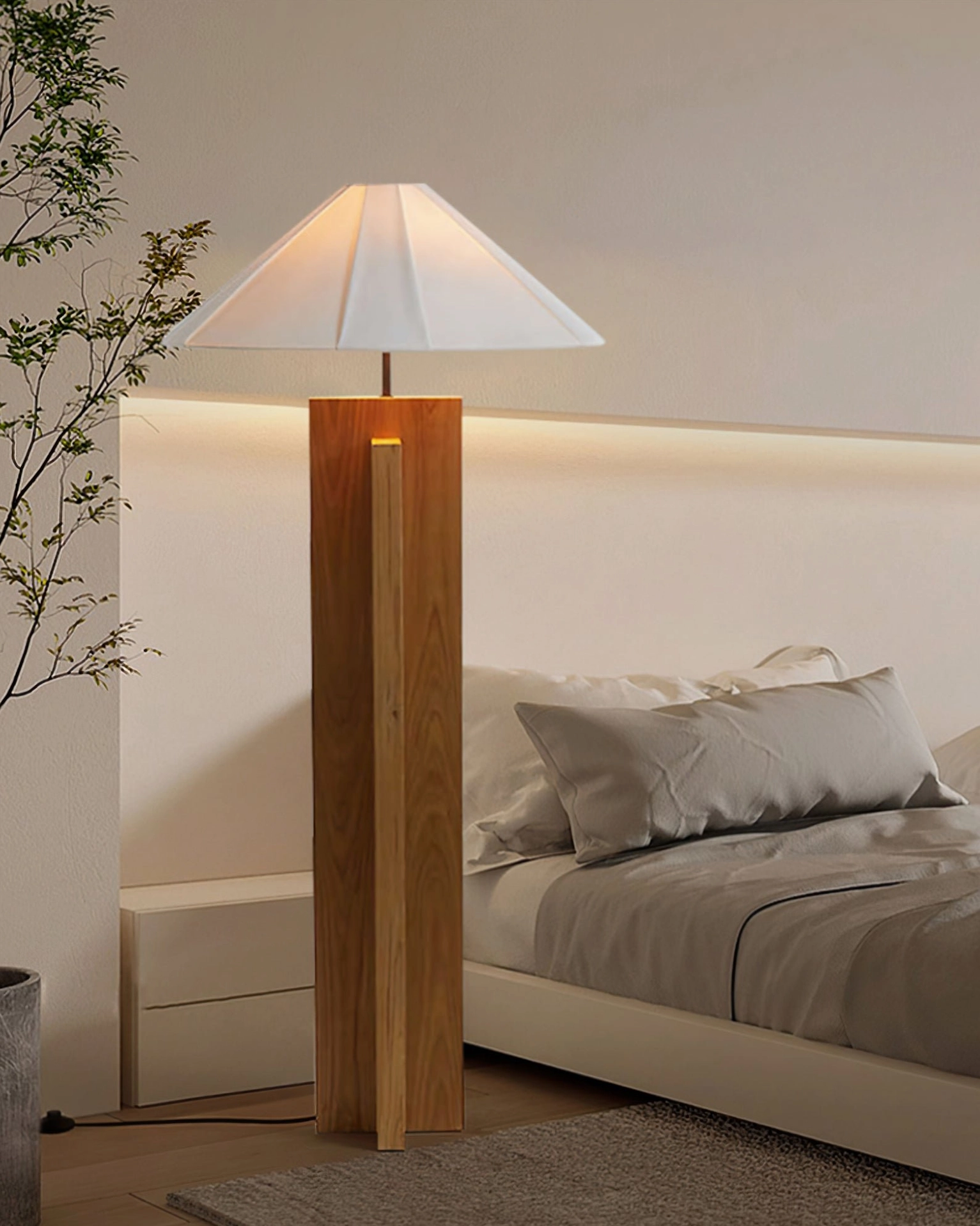 Light wood natural tone floor lamp with geometric base in modern bedroom with bed and green plant
