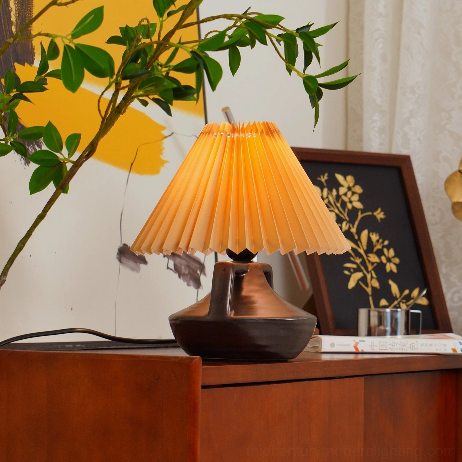 Navia ceramic table lamp styled with wooden cabinet, green branches, and amber-toned vintage decor