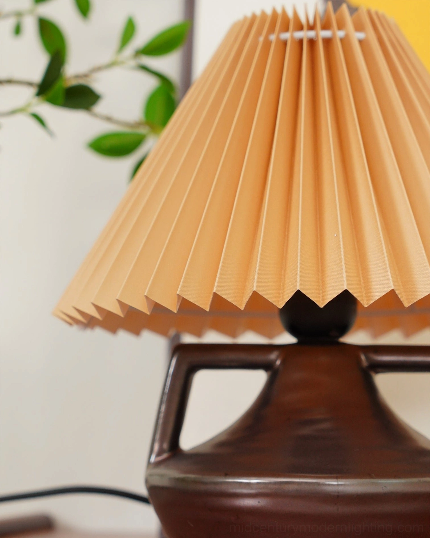 Navia pleated table lamp three-quarter view showing fabric shade pleats and ceramic base