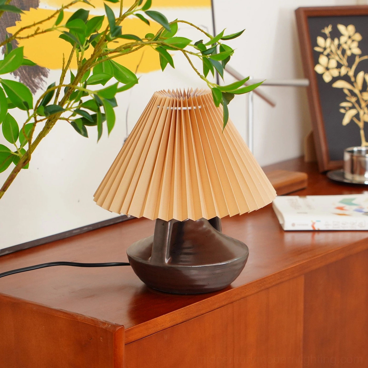 Navia ceramic table lamp styled on wooden vintage cabinet with green plants and warm retro home decor