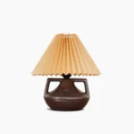Navia pleated table lamp with ceramic base and khaki fabric shade, front view on white background