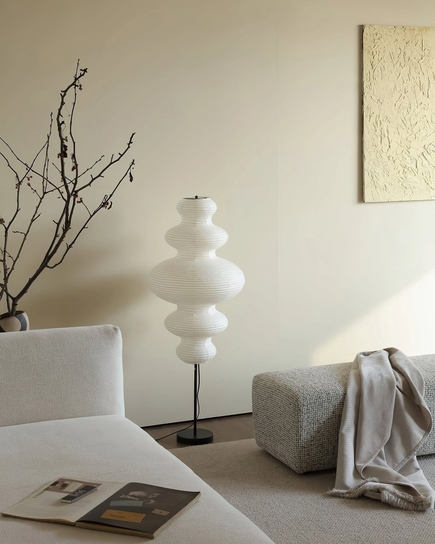 Side perspective view of Neiko floor lamp in low-sofa living room with dried branch wall decoration
