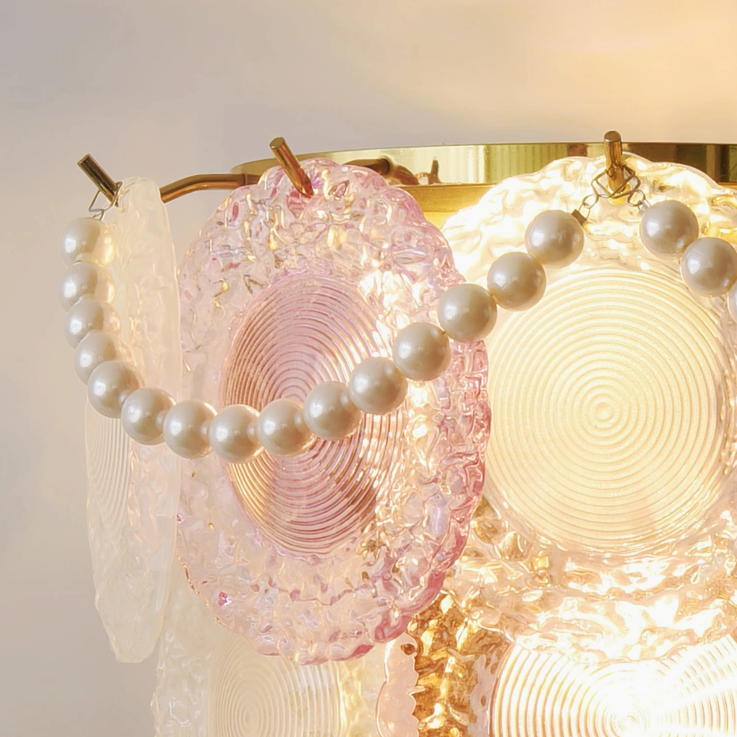 Lit Nenufar wall lamp with layered glass shades and pearl string decoration, ambient warm lighting