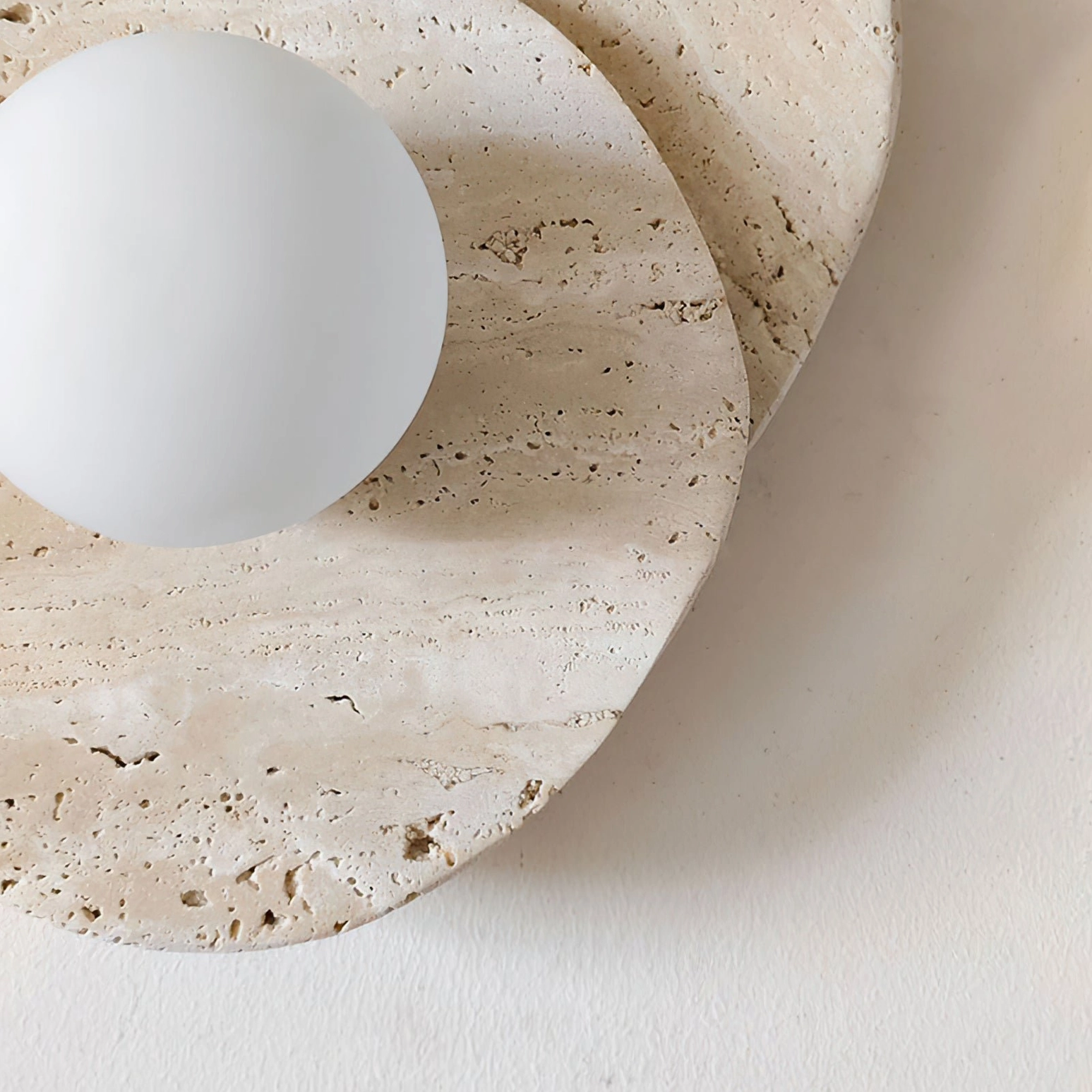 Overhead view of Ner wall sconce highlighting natural travertine pore texture and geological layering characteristic of the stone