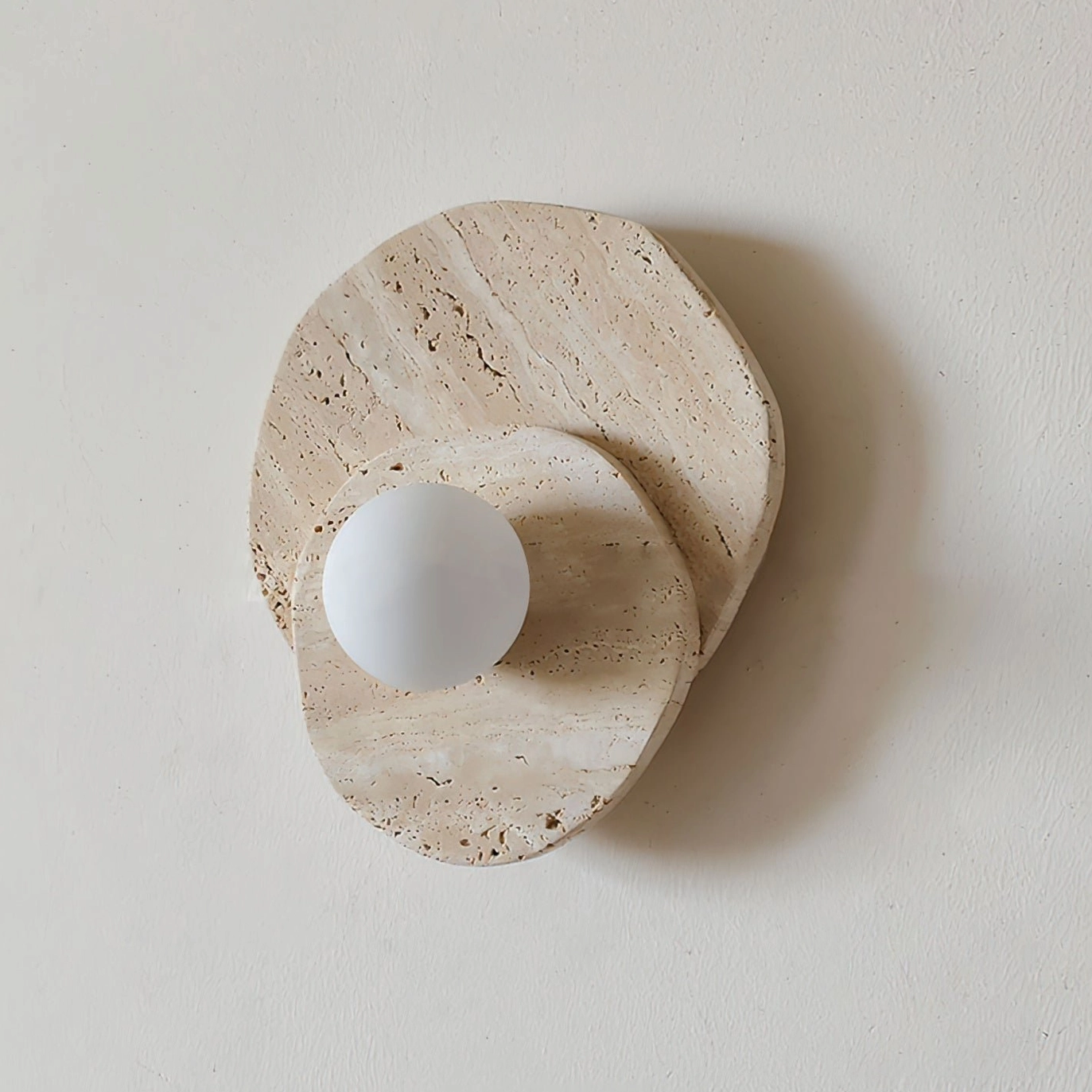 Ner travertine wall light photographed from right side angle, modern geometric form against minimalist interior wall